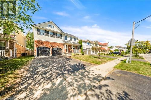 View of front of property featuring asphalt driveway, brick siding, a residential view, and an attached garage - 132 Blackburn Drive, Brantford, ON - Outdoor