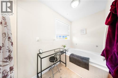 Bathroom featuring a garden tub, a shower with curtain, and tile patterned floors - 132 Blackburn Drive, Brantford, ON - Indoor Photo Showing Bathroom