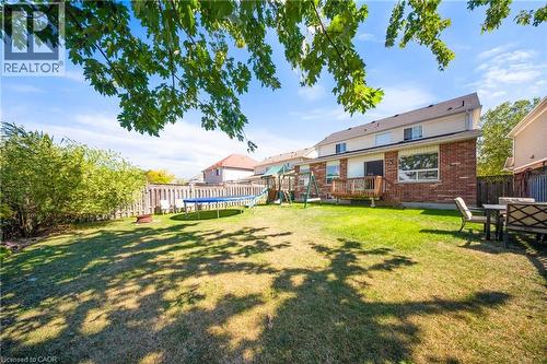 Fenced backyard with a trampoline, a playground, and a deck - 132 Blackburn Drive, Brantford, ON - Outdoor