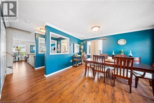Dining area with a textured ceiling, ornamental molding, wood finished floors, and stairs - 132 Blackburn Drive, Brantford, ON - Indoor Photo Showing Dining Room