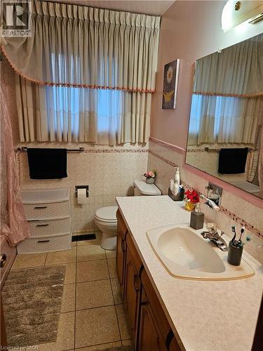 Bathroom featuring vanity, a shower with shower curtain, tile walls, wainscoting, and light tile patterned flooring - 197 Craigroyston Road, Hamilton, ON - Indoor Photo Showing Bathroom