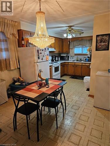 Kitchen with light floors, white appliances, wood finish cabinets, light countertops, and suspended lighting - 197 Craigroyston Road, Hamilton, ON - Indoor