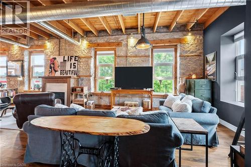 Living room with a fireplace, wood finished floors, and a wooden ceiling with exposed beams - 25 Concession Street Unit# 201, Cambridge, ON - Indoor With Fireplace