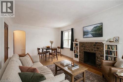 Digitally staged, Living room with arched walkways, wood finished floors, and a stone fireplace - 90 Osler Drive, Dundas, ON - Indoor Photo Showing Living Room With Fireplace
