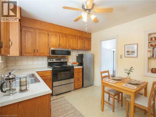 Digitally staged Kitchen with stainless steel appliances, light countertops, wood finish cabinets, ceiling fan, and decorative backsplash - 90 Osler Drive, Dundas, ON - Indoor Photo Showing Kitchen With Double Sink