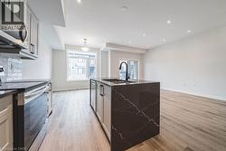 Modern kitchen with a dark countertop island featuring an integrated sink and matte black faucet - 