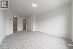 Spacious interior room featuring light-colored patterned carpeting, white walls, and bright overhead lighting - 