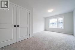 Bright room featuring light grey carpeting, white walls, and a large window - 