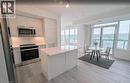 Kitchen featuring stainless steel appliances, white cabinets, light wood-style floors, backsplash, and a kitchen island - 385 Winston Road Unit# 1311, Grimsby, ON  - Indoor Photo Showing Kitchen 
