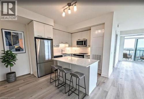 Kitchen featuring stainless steel appliances, a breakfast bar area, white cabinetry, and light wood-style flooring - 385 Winston Road Unit# 1311, Grimsby, ON - Indoor Photo Showing Kitchen With Stainless Steel Kitchen With Upgraded Kitchen