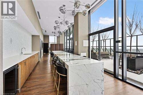 Kitchen with modern cabinets, a breakfast bar area, light stone countertops, beverage cooler, and wood finish cabinetry - 385 Winston Road Unit# 1311, Grimsby, ON - Indoor