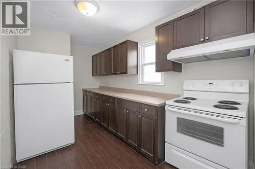 Kitchen featuring white appliances, dark wood finish cabinets, and light countertops - 43 Sterling Street, Hamilton, ON - Indoor Photo Showing Kitchen