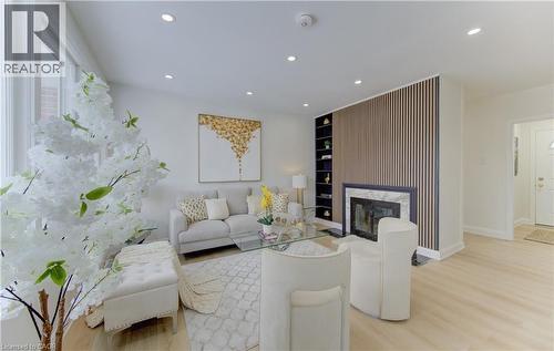 Living room featuring light wood-style flooring, recessed lighting, a premium fireplace, and built in shelves - 171 Sixth Avenue, Kitchener, ON - Indoor Photo Showing Living Room With Fireplace