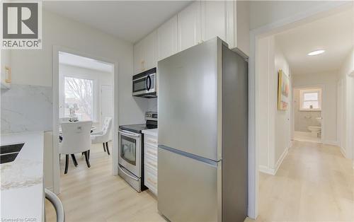 Kitchen featuring stainless steel appliances, white cabinetry, light wood-style flooring, and light stone counters - 171 Sixth Avenue, Kitchener, ON - Indoor Photo Showing Kitchen