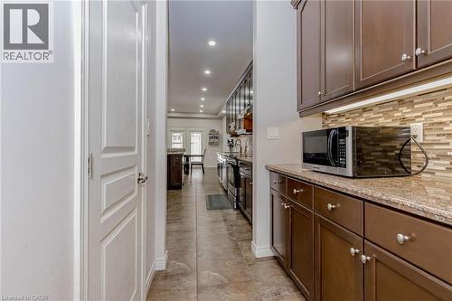 Kitchen with light stone counters, stainless steel appliances, recessed lighting, dark wood finish cabinets, and tasteful backsplash - 2 Doon Creek Street, Kitchener, ON - Indoor Photo Showing Kitchen