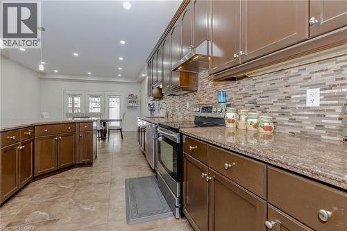 Kitchen featuring stainless steel appliances, light stone counters, decorative light fixtures, and tasteful backsplash - 2 Doon Creek Street, Kitchener, ON - Indoor Photo Showing Kitchen With Upgraded Kitchen