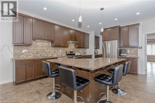 Kitchen featuring light stone counters, stainless steel appliances, a center island, and decorative backsplash - 2 Doon Creek Street, Kitchener, ON - Indoor Photo Showing Kitchen With Upgraded Kitchen