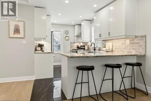 Kitchen with white cabinets, light stone countertops, stainless steel range with gas stovetop, a peninsula, and recessed lighting - 237 East 32Nd Street, Hamilton, ON - Indoor Photo Showing Kitchen With Upgraded Kitchen