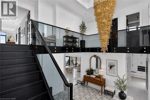 Grand foyer featuring a dramatic multi-tiered chandelier, black wood-finish staircase, and a glass and black metal railing system - 711 Beach Boulevard, Hamilton, ON - Indoor Photo Showing Other Room