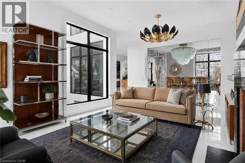 Spacious living area featuring polished white flooring, a built-in shelving unit with wood-finish backing and chrome accents, a full-height window with black frames, and a distinctive overhead light f - 711 Beach Boulevard, Hamilton, ON - Indoor Photo Showing Living Room