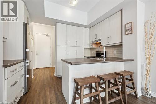 Kitchen with a breakfast bar area, a peninsula, dark countertops, and dark wood-style flooring - 40 Esplanade Lane Unit# 102, Grimsby, ON - Indoor Photo Showing Kitchen