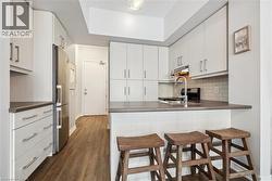 Kitchen with a kitchen bar, a peninsula, dark countertops, decorative backsplash, and dark wood-style floors - 