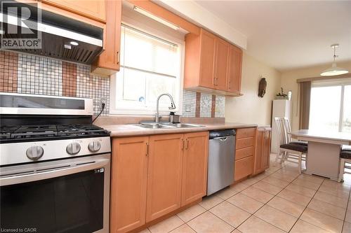 Kitchen featuring stainless steel appliances, exhaust hood, light wood finish cabinets, light countertops, and decorative backsplash - 142 Hawkswood Trail, Hamilton, ON - Indoor Photo Showing Kitchen With Double Sink