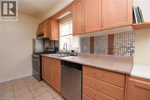 Kitchen with stainless steel appliances, light countertops, backsplash, light tile patterned floors, and light wood finish cabinets - 142 Hawkswood Trail, Hamilton, ON - Indoor Photo Showing Kitchen With Double Sink