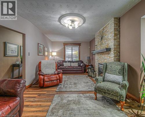 Living area with a textured ceiling, wood finished floors, and a fireplace - 81 Beechwood Avenue, Hamilton, ON - Indoor Photo Showing Living Room With Fireplace