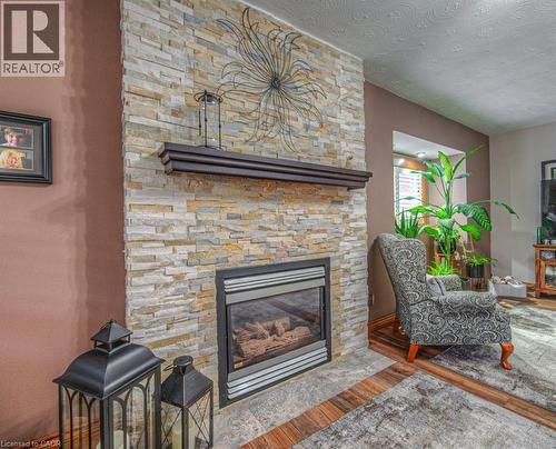 Living area with a fireplace, wood finished floors, and a textured ceiling - 81 Beechwood Avenue, Hamilton, ON - Indoor Photo Showing Living Room With Fireplace