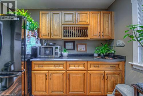 Kitchen featuring stainless steel microwave, wood finish cabinetry, dark countertops, and freestanding refrigerator - 81 Beechwood Avenue, Hamilton, ON - Indoor