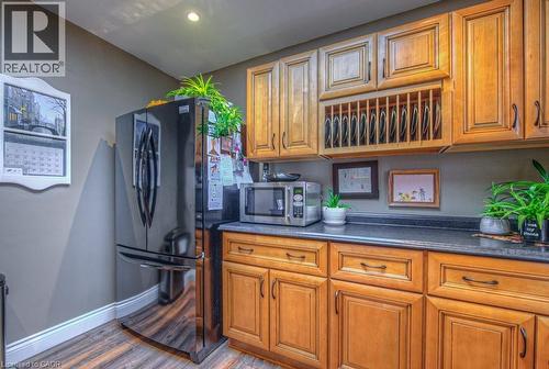Kitchen featuring dark countertops, wood finish cabinets, stainless steel microwave, freestanding refrigerator, and wood finished floors - 81 Beechwood Avenue, Hamilton, ON - Indoor Photo Showing Kitchen