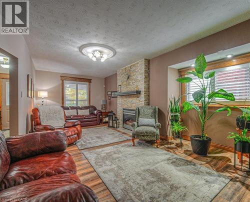 Living area featuring a textured ceiling, wood finished floors, and a fireplace - 81 Beechwood Avenue, Hamilton, ON - Indoor Photo Showing Living Room With Fireplace