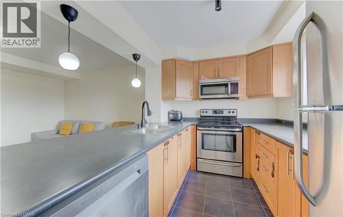 Kitchen featuring stainless steel appliances, decorative light fixtures, light wood finish cabinetry, dark tile patterned flooring, and light countertops - 9 Outlook Terrace, Kitchener, ON - Indoor Photo Showing Kitchen With Stainless Steel Kitchen