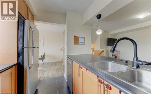 Kitchen featuring stainless steel appliances, dark countertops, light wood finish cabinetry, dark tile patterned flooring, and decorative light fixtures - 9 Outlook Terrace, Kitchener, ON - Indoor Photo Showing Kitchen With Double Sink