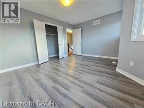 Unfurnished bedroom featuring dark wood finished floors and a closet - 486 Dicenzo Drive, Hamilton, ON - Indoor Photo Showing Other Room