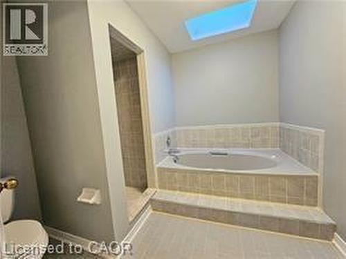 Full bathroom featuring a skylight, a bath, a walk in shower, and tile patterned floors - 486 Dicenzo Drive, Hamilton, ON - Indoor Photo Showing Bathroom