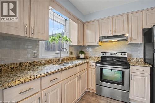 Kitchen with stainless steel range with electric stovetop, light wood finish cabinets, light stone countertops, light wood-type flooring, and freestanding refrigerator - 21 Greystone Crescent, St. Catharines, ON - Indoor Photo Showing Kitchen With Double Sink