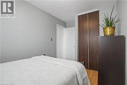 Bedroom with light wood-style flooring, a textured ceiling, and a closet - 21 Greystone Crescent, St. Catharines, ON - Indoor Photo Showing Bedroom