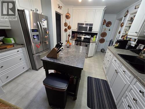 Kitchen with white cabinets, stainless steel appliances, light flooring, dark stone countertops, and crown molding - 27 Hepburn Avenue, St. Thomas, ON - Indoor Photo Showing Kitchen