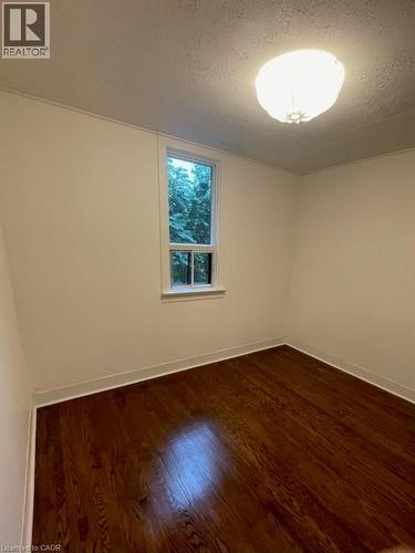 Empty room with a textured ceiling and dark wood finished floors - 18 Mulberry Street, Hamilton, ON - Indoor Photo Showing Other Room
