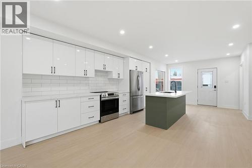 Two tone kitchen with stainless steel appliances, light wood finished floors, tasteful backsplash, an island with sink, and recessed lighting - 1278 Main Street E, Hamilton, ON - Indoor Photo Showing Kitchen With Stainless Steel Kitchen With Upgraded Kitchen