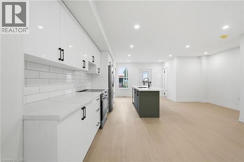 Kitchen with stainless steel appliances, two tone cabinetry, light wood-style floors, recessed lighting, and a kitchen island with sink - 1278 Main Street E, Hamilton, ON - Indoor Photo Showing Kitchen With Upgraded Kitchen