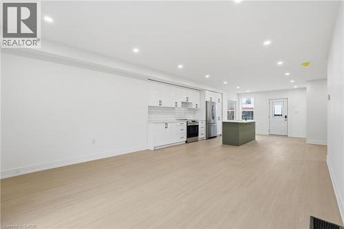 Kitchen with a kitchen island, open floor plan, light countertops, stainless steel appliances, and light wood-style flooring - 1278 Main Street E, Hamilton, ON - Indoor Photo Showing Other Room