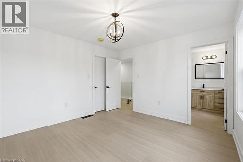 Unfurnished bedroom with light wood-type flooring, a chandelier, and ensuite bath - 1278 Main Street E, Hamilton, ON - Indoor Photo Showing Other Room