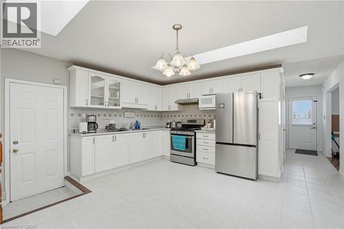 Kitchen with a skylight, glass insert cabinets, stainless steel appliances, light countertops, and white cabinets - 513 Rexford Drive, Hamilton, ON - Indoor Photo Showing Kitchen