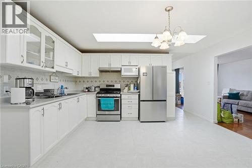 Kitchen featuring a skylight, stainless steel appliances, light countertops, white cabinetry, and a chandelier - 513 Rexford Drive, Hamilton, ON - Indoor Photo Showing Kitchen With Double Sink