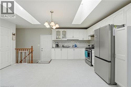 Kitchen with a skylight, glass fronted cabinets, stainless steel appliances, hanging lights, and light countertops - 513 Rexford Drive, Hamilton, ON - Indoor Photo Showing Kitchen