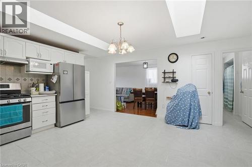 Kitchen with stainless steel appliances, white cabinetry, a skylight, and a chandelier - 513 Rexford Drive, Hamilton, ON - Indoor Photo Showing Kitchen