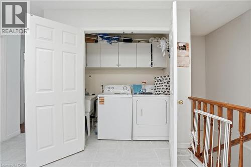 Laundry area featuring cabinet space, washer and clothes dryer, and light tile patterned flooring - 513 Rexford Drive, Hamilton, ON - Indoor Photo Showing Laundry Room